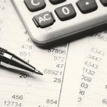 flatlay calculator, pen, and financial reports