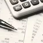 flatlay calculator, pen, and financial reports