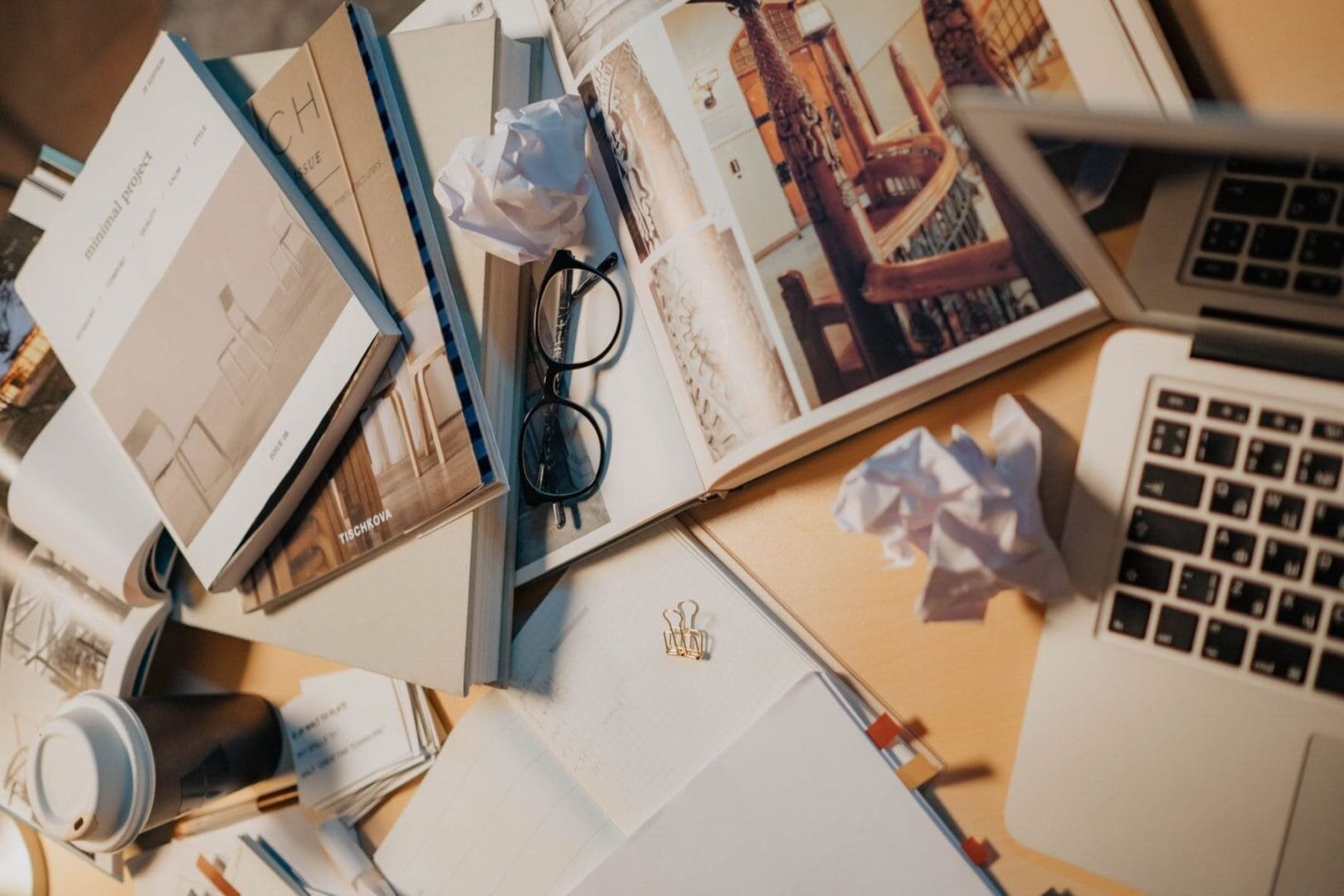 The back-office chaos trap looks like a cluttered desk with books, eyeglasses, crumpled papers, and a laptop, representing the back-office chaos trap that overwhelms service-based business owners